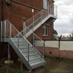 External steel fire escape staircase with vertical infill bar balustrasde and closed riser checker plate treads
