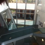 Frameless glass balustrade with stainless steel slotted tube top rail to walkway