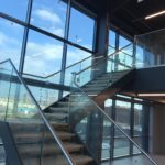 Steel staircase with powder coated double stringers, frameless glass balustrade, stainless steel slotted channel tube top rail